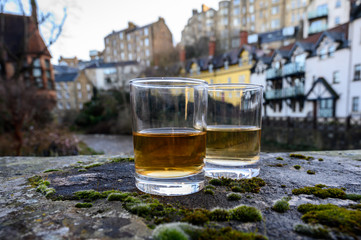 Scotch single malts or blended whisky spirits in glasses with old houses of Edinburgh on...