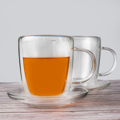Cup of tea with teapot on a wooden table.