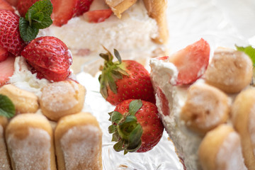 Strawberry charlotte cake. Summer dessert with Savoiardi on a glass tray decorated with mint leaves