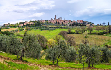Fototapeta na wymiar Amazing spring landscape with green rolling hills and old town of San Gimignano in the distance, Tuscany, Italy