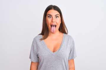Portrait of beautiful young woman standing over isolated white background sticking tongue out happy with funny expression. Emotion concept. © Krakenimages.com
