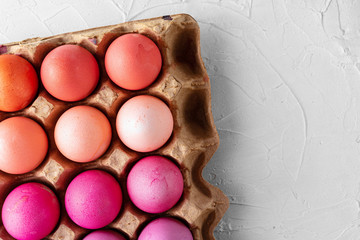 Several Easter eggs in different shades of pink in eggbox