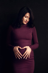 Obraz premium Pregnant happy Woman touching her belly. Pregnant middle aged mother portrait, caressing her belly and smiling close-up. Healthy Pregnancy concept, brunette expectant female 