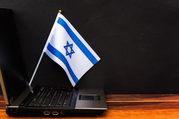  flag of Israel , computer, laptop on table and dark background