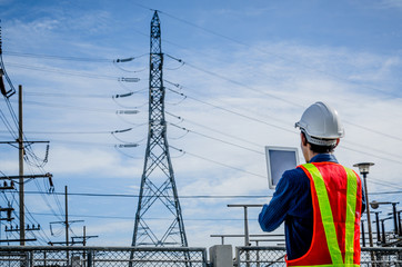 Engineers use the tablet at the high voltage pole against the blue background.