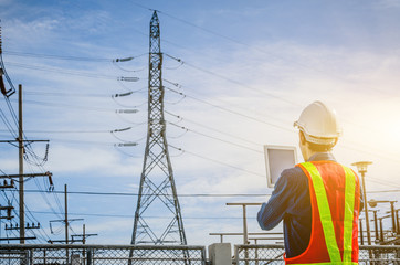 Engineers use the tablet at the high voltage pole against the blue background.