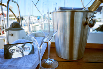 Romantic luxury evening on cruise yacht with champagne setting. Empty glasses and bottle with champagne and tropical sunset with sea background