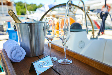 Romantic luxury evening on cruise yacht with champagne setting. Empty glasses and bottle with champagne and tropical sunset with sea background