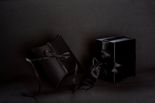 Two black gift boxes with black ribbon bow on dark background, copy space. Valentine's day, birthday romantic concept, greeting card.
