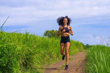 happy female runner training on countryside road - young attractive and fit jogger woman doing...