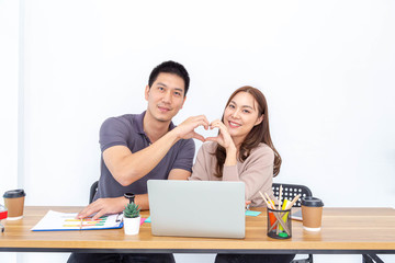 Young Asian couple office worker hands creating heart heart shape. Feeling happy, love concept.