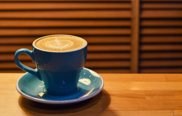 Coffee in blue cup on wooden table with copy space.