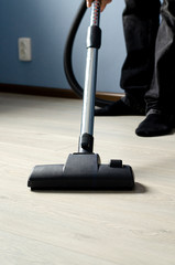 A man with a vacuum cleaner in his hands conducts cleaning in a room