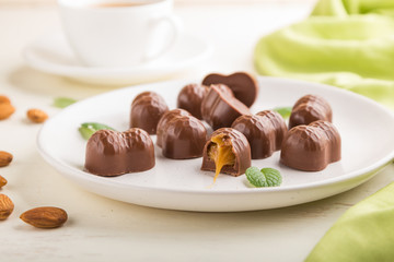 Chocolate candies with almonds and caramel on a white wooden background. side view, selective focus