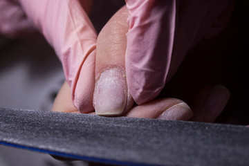 Master of manicure and saws nails with a nail file. Giving a square shape to the nails. Professional manicure in the salon close-up.