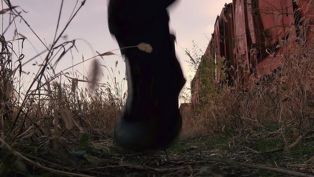 Homeless immigrant with hoodie running by old train wagons