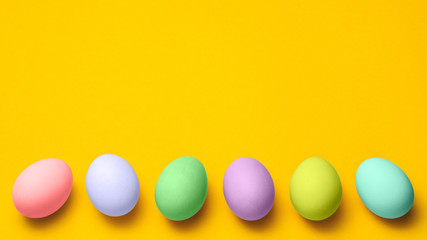easter eggs painted in pastel colors on a yellow background with copyspace. easter advertise minimalist concept design