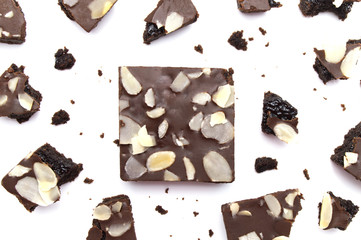 Chocolate brownies with sliced almond nuts toppings broken and crumbs isolated on white background.