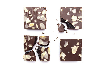 Chocolate brownies with sliced almond nuts toppings broken and crumbs isolated on white background.