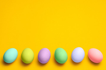 easter eggs painted in pastel colors on a yellow background with copyspace. easter advertise minimalist concept design