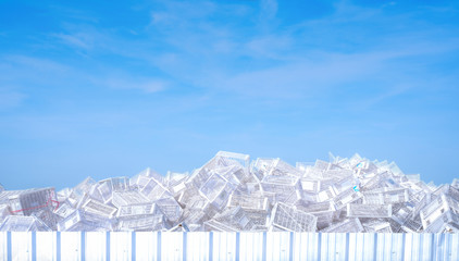 Pile of white plastic basket at factory outdoor warehouse. Many of empty plastic basket against blue sky and white clouds. Basket for store products. Stacked of plastic crates. Cargo and shipping.