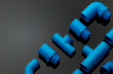 Set of blue PVC pipe fittings isolated on dark background. Blue plastic water pipe. PVC accessories...