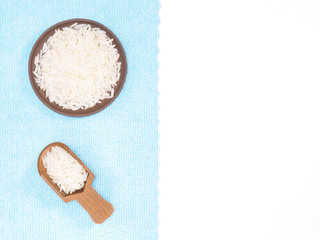 Indian long grain Basmati rice in wooden scoop vertically and clay plate on white and blue fabric background. Indian cuisine, ayurveda, naturopathy concept