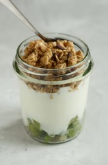 Natural yogurt with granola and kiwi in a glass jar