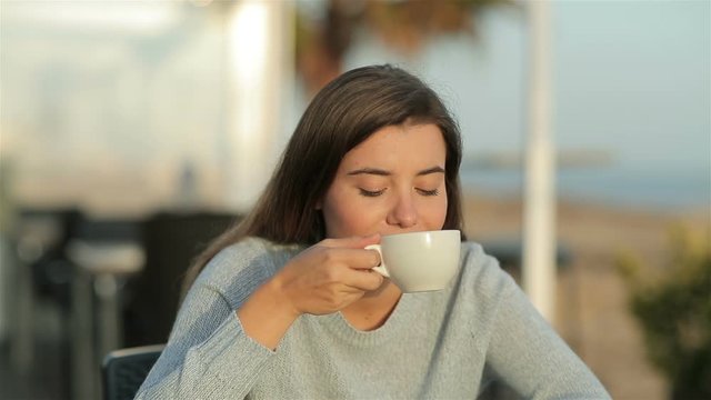 Satisfied girl in a restaurant terrace smelling coffee in slow motion