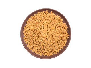Spice fenugreek in clay plate isolated on white