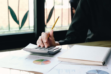 Fototapeta premium Close up Businesswoman using calculator and laptop for do math finance on wooden desk in office and business working background, tax, accounting, statistics and analytic research concept