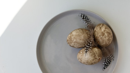 Naturally dyed eggs prepared for Easter on white background. Happy Easter card. Easter background with Easter eggs in a ceramic gray bowl. Background with easter eggs. Top view 