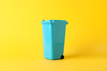 Blue recycle bin on yellow background, space for text