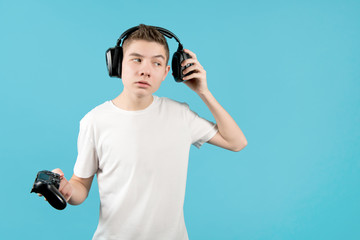 a teenager in headphones with a joystick in his hands listens to something, freeing one ear
