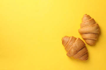 Baked croissants on yellow background, top view