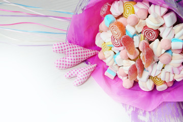 Bouquet of sweets in the pink paper with two hearts