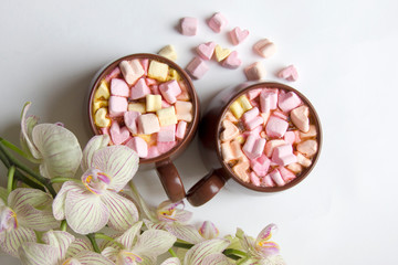 Top view of brown cups of hot cocoa with marshmallows in heart shape on white background.
