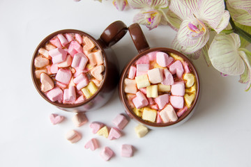 Top view of brown cups of hot cocoa with marshmallows in heart shape on white background.
