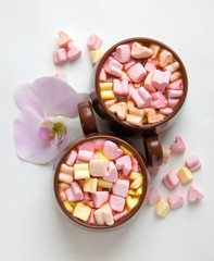 Top view of brown cups of hot cocoa with marshmallows in heart shape on white background.