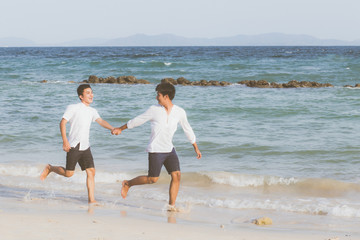 Homosexual portrait young asian couple running with cheerful together on beach in summer, asia gay going tourism for leisure and relax with happiness in vacation at sea, LGBT legal concept.