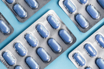 Blue tablets in a blister pack, pills in foil blister packs, medications drugs on blue surface....