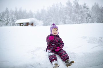 Fototapeta na wymiar A small girl is sitting on the snow