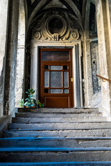 Steintreppe empor zu einer hölzernen Tür umrahmt von Stein Ornamenten