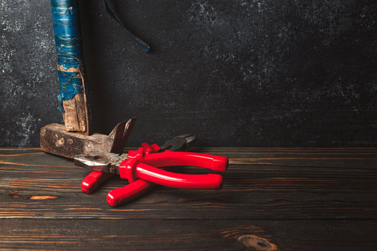 Work tool, on a dark wooden background. Pliers, wire cutters, old hammer.