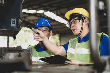 Industrial engineers in safety uniforms wearing yellow safety helmets are inspecting work by tools.  and on the job training he works in industrial machinery.