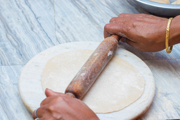 Indian woman making bread or roti by wheel roller.