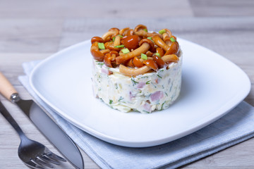 Salad with mushrooms (honey fungus), ham, potatoes, cheese and mayonnaise. Traditional Russian salad «mushroom bast basket». Selective focus, close-up.