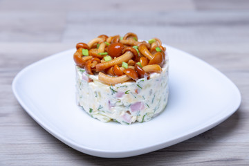 Salad with mushrooms (honey fungus), ham, potatoes, cheese and mayonnaise. Traditional Russian salad «mushroom bast basket». Selective focus, close-up.