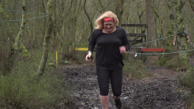 Two women running through a mud run / assault / obstacle course. They are racing through the muddy track, competing - Stock 4K Video clip footage