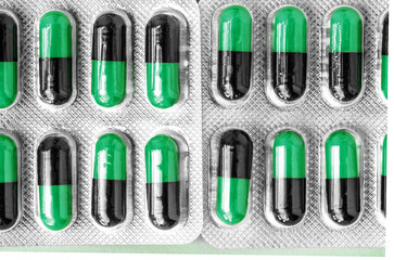aluminum blisters with colored black and green oval capsules neat flat lay